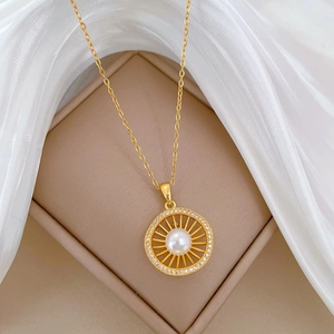 Elegant gold titanium necklace with pearl and zirconia sun pendant on jewelry box