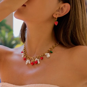 Detail of gold chain necklace with red strawberry, cherry charms and baroque pearls