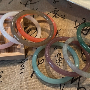 Polished colorful agate bangles stacked on a Chinese calligraphy backdrop for women