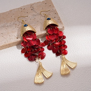 Macro detail of red shell fish-shaped tassel earrings on a textured stone base