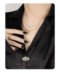 Detail of layered gold and silver necklaces with irregular textured wave ring on model