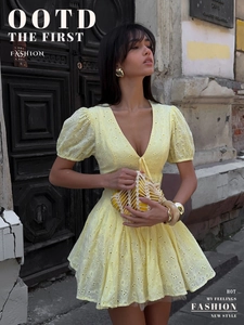 Detail of yellow cotton mini dress featuring floral eyelet embroidery and a deep V-neckline