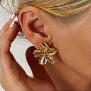 Chic oversized gold floral stud earrings with textured petals on model