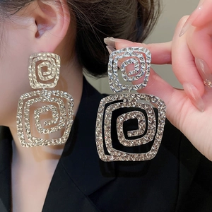 Close-up of silver-tone square spiral earrings with textured finish on female model