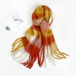 Detail of colorful striped mohair scarf with tassels next to a fashion magazine