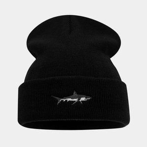 Close-up of a black knit beanie featuring detailed shark embroidery and ribbed texture