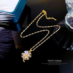 Detailed view of a gold clover pendant with pink heart crystal and adjustable wave chain
