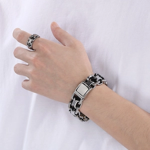 Close-up of a men's stainless steel X-shaped hollow ring and chunky chain bracelet set