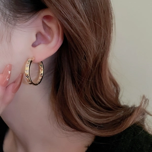 Close-up of gold hoop earrings featuring multi-colored zircon heart gemstones on a model