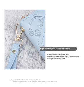 Close-up of light blue leather wallet featuring bear embroidery and gold metal clasp