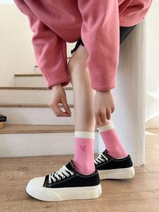 Detail of pink cotton crew socks featuring cute heart embroidery and white striped cuffs