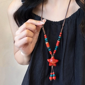 Détail d'un collier artisanal avec pendentif étoile en céramique rouge et perles