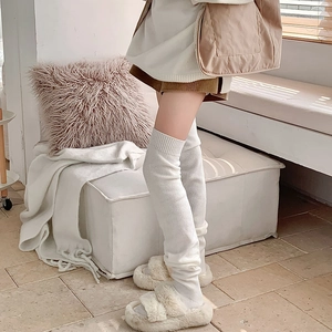 Detail of warm white knit leg warmer with ribbed cuff and cozy indoor styling