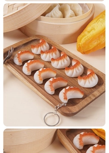 Realistic shrimp dumpling keychain on wooden tray with traditional bamboo steamer background