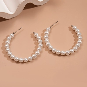 Macro view of large circular hoop earrings featuring elegant white pearls and silver needles
