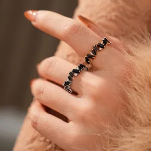 Modern gold and silver interlocking rings with black baguette zircons on finger