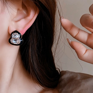 Close-up of a sparkling black gourd-shaped stud earring worn by a model with diamonds