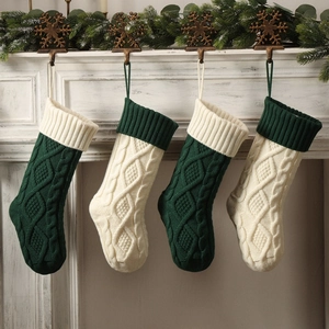 Classic knitted Christmas stockings in dark green and cream hanging on a white fireplace