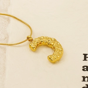 Golden stainless steel croissant pendant necklace with sleek snake chain on beige background