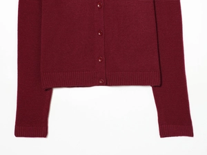 Détail du cardigan en maille fine bordeaux avec boutons simples et finition bord-côte