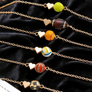 Détail de colliers de sport cœur dorés avec boules en émail coloré sur velours noir