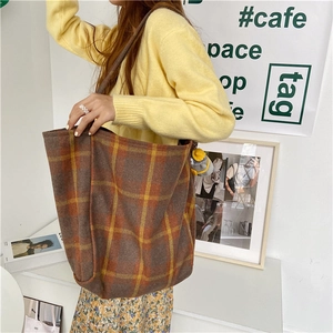 Brown and orange plaid wool tote bag being carried as a stylish accessory in a room