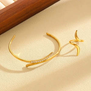 Detail of a gold jewelry set with a sparkling zircon inlaid bangle and streamline ring