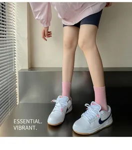 Gros plan de baskets Nike SB blanches avec logo bleu et chaussettes roses sur modèle