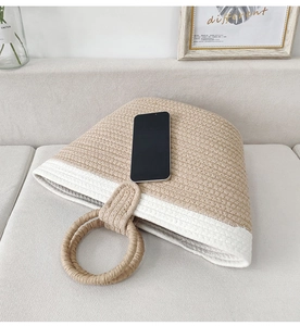 Detail of woven cotton rope tote bag with round handles on a cozy beige sofa