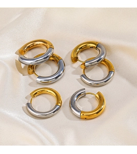 Detail of two-tone gold and silver circular earrings on a beige silk fabric backdrop
