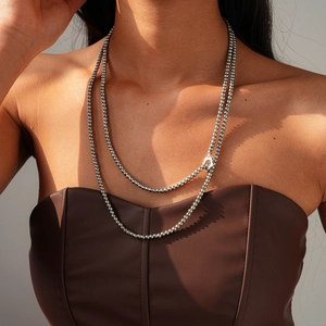 Detail of silver layered metal beaded necklace on model with elegant OT buckle closure