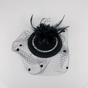 Detail of black vintage fascinator hat with mesh veil, white pearls and feather accents