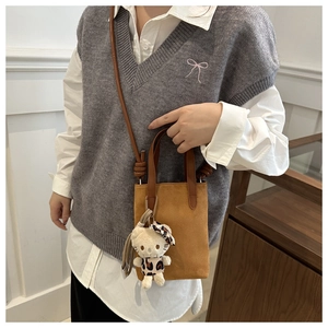 Detail of a brown suede crossbody bag with a cute leopard-print plush kitten pendant