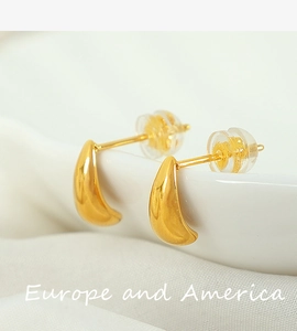 Macro shot of minimalist gold drop earrings with polished finish and silicone backings