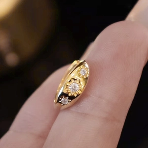 Macro detail of gold ring featuring three carved sunflowers with central zircon stones