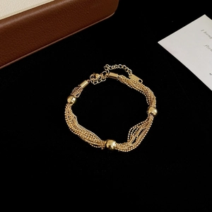 Detail view of multilayer golden chain bracelet with metallic beads and lobster clasp