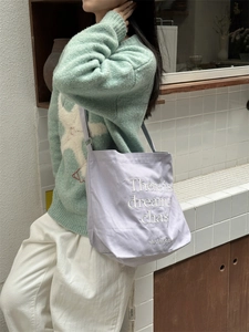 Detail of light purple canvas tote with 'Dream Chaser' embroidery and adjustable strap