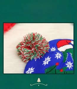 Close-up of festive blue knit Christmas hat with large colorful pompom and snowflakes