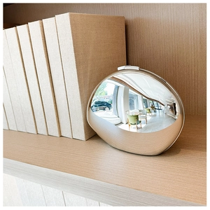 Detail of silver metallic egg-shaped bag showing matte brushed finish and mirror top