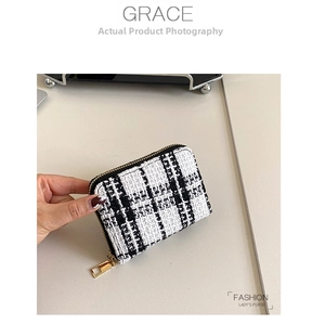 Close-up of black and white tweed short wallet with gold zipper and woven texture