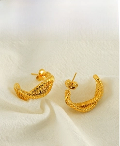 Close-up of golden irregular U-shaped earrings with intricate twisted rope texture detail