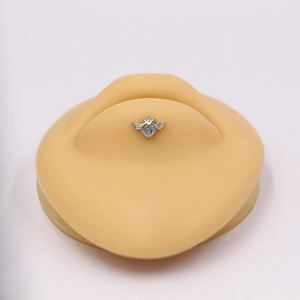 Silver winged heart stud with crown and rhinestones on a professional lip model