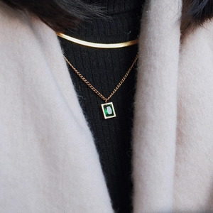 Gold layered necklace with flat snake chain and emerald zircon pendant on model