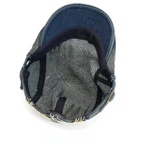 Detail view of denim flat cap interior with 100% cotton label and metal buckle adjustment