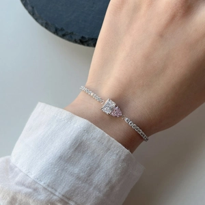 Close-up of S925 silver tennis bracelet with pink heart and radiant cut stones on wrist