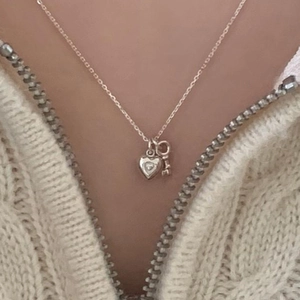 Minimalist 925 sterling silver heart and key pendant necklace on model with white knitwear