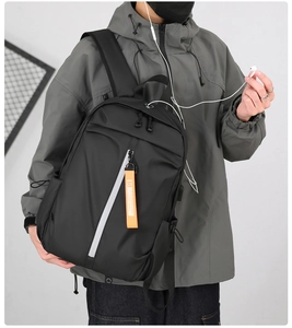 Detail view of the black waterproof nylon backpack featuring a headphone jack and orange tag