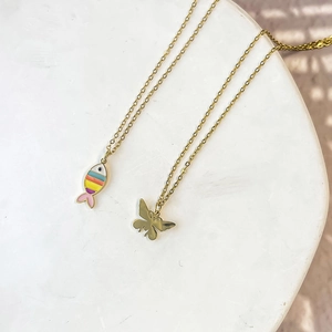 Detail of gold chain necklaces with colorful enamel fish and butterfly pendants