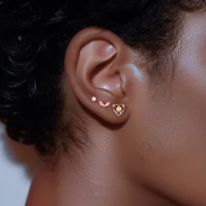 Close-up of S925 silver ear studs set with pink zircon and heart opal on ear