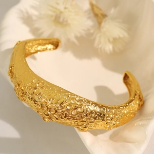 Irregular golden lava cuff bracelet with floral relief pattern on shell display